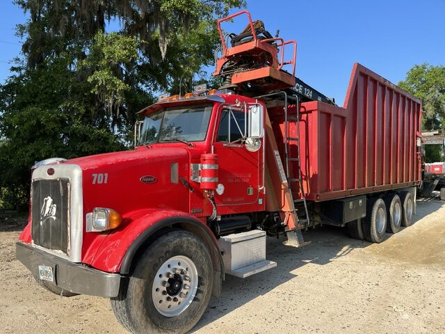 Envirowaste grapple truck loading brush and storm cleanup debris